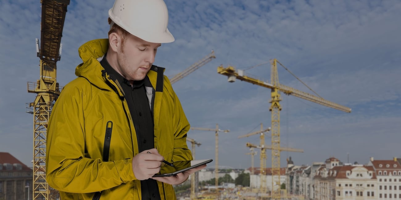 A construction worker with yellow outfit, helmet and a tablet